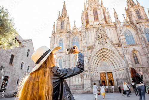 Young woman tourist photographing with phone famous saint Eulalia church during the morning light in Barcelona city photo