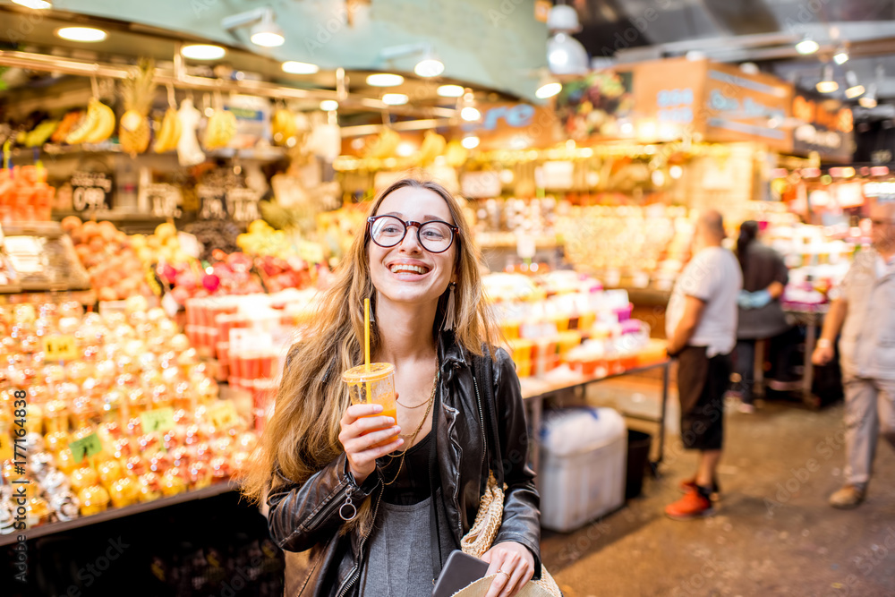 Naklejka premium Młoda kobieta pije sok pomarańczowy na słynnym targu spożywczym w Barcelonie