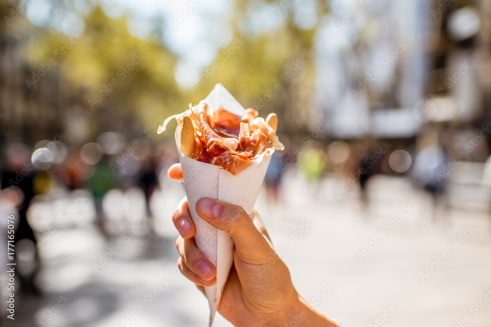 Fototapeta premium Holding jamon traditional spanish jerked meat outdoors on the street in Barcelona