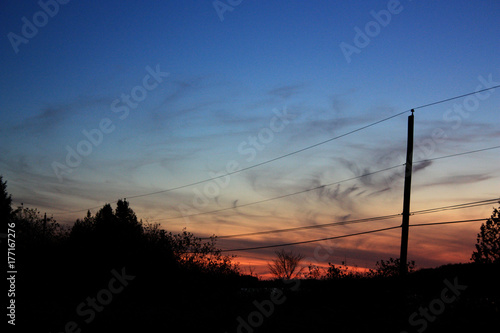 Telephone Poles sillouetted against a blue sky at sunset.