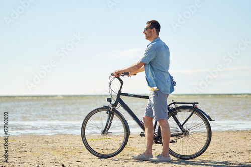 happy young man with bicycle on beach 