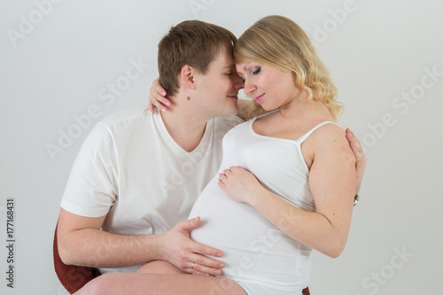 Beautiful pregnant couple in love on the background.Hands of husband on the tummy of his pregnant wife. Young man tenderly stroked pregnant belly of his wife. Husband kissing pregnant belly.