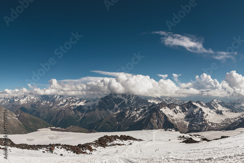 Dark blue sky with clouds on the rocky peaks of the mountains covered with glaciers and snow