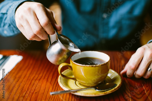 pouring creamer in coffee mug