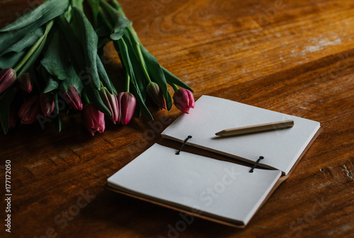 Pink tulips and a blank journal on a table photo