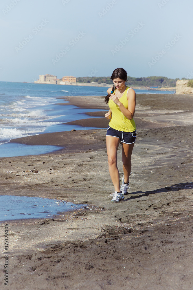 Woman jogging on beach listening music