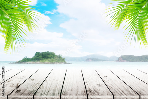 Empty wooden table and coconut leaves with party on beach blurred background in summer time.