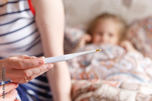 How to treat a child from a cold to bring down the temperature Close up of a mother s hand with a thermometer.