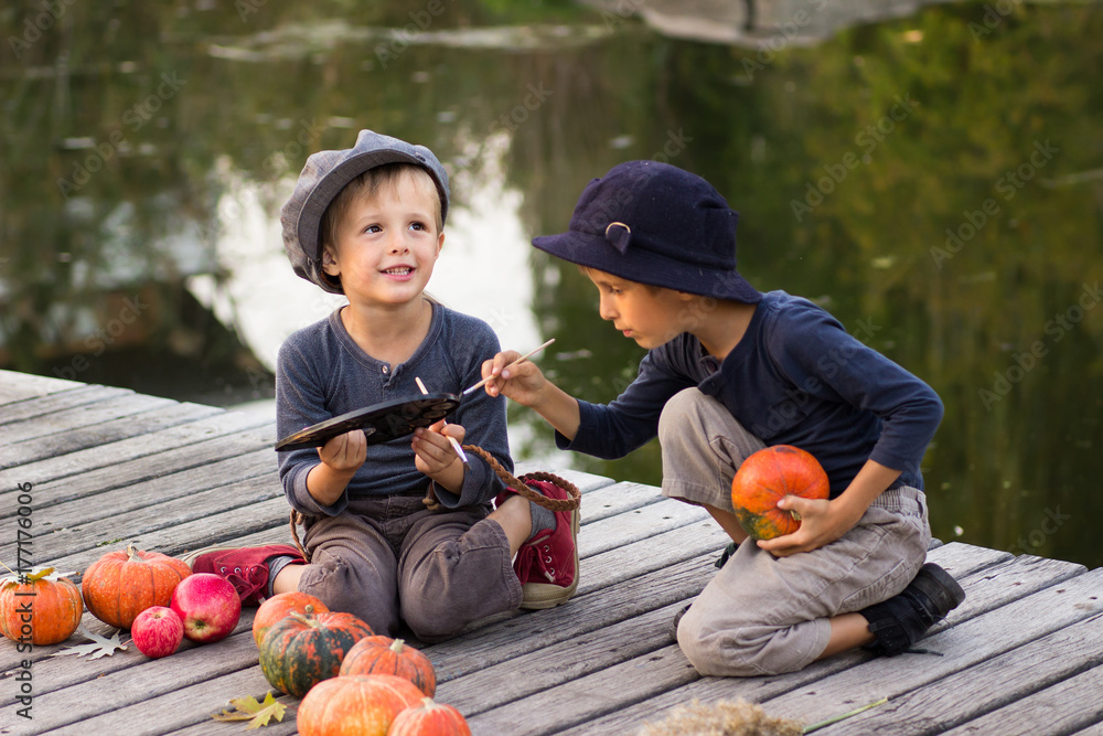 Fototapeta premium Laughing children paint small Halloween pumpkins