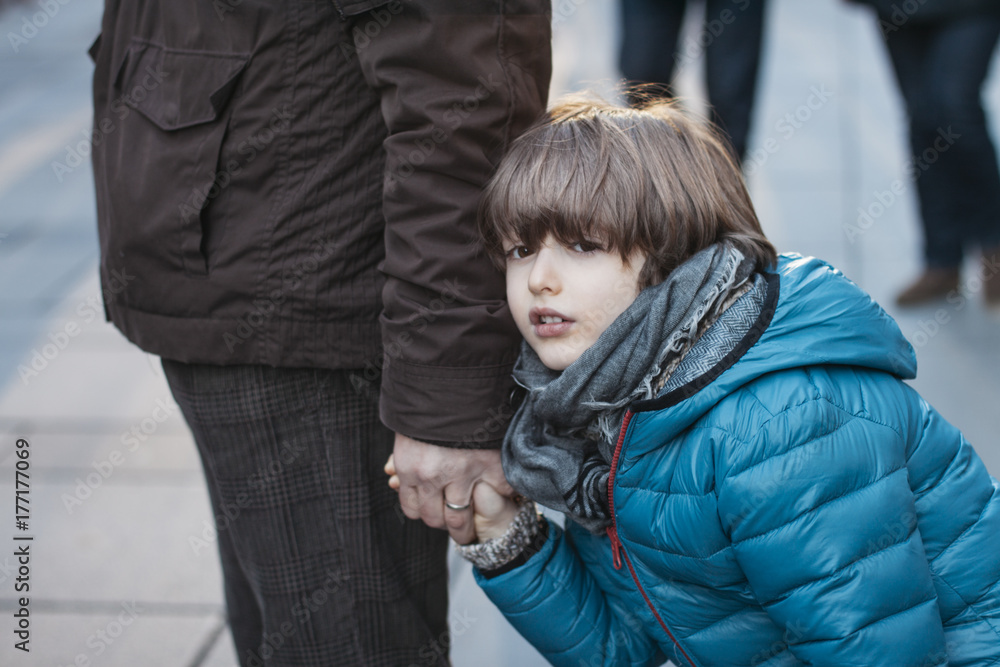 Tired boy walking unwillingly next to his father Tired boy walking unwillingly next to his father