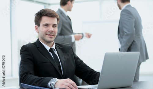 successful businessman sitting at the table with an open laptop 