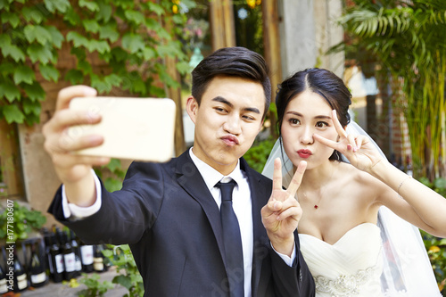 young asian bride and groom taking a selfie Fototapete