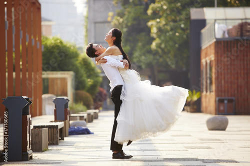 Фотография asian bride and groom hugging outdoors
