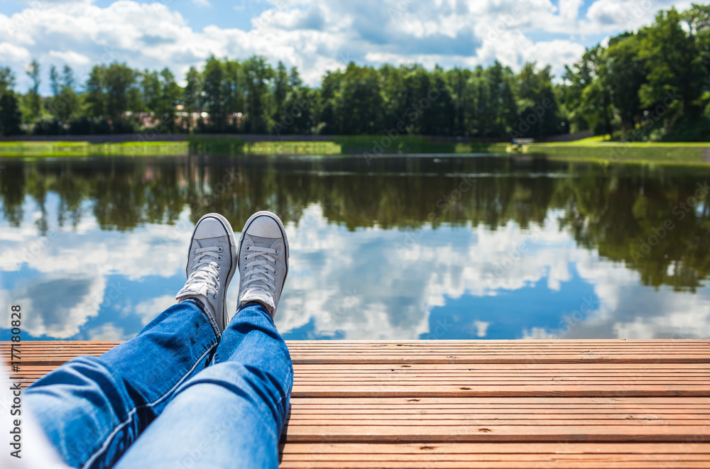 Obraz premium Woman relaxing her feet by the lake. 