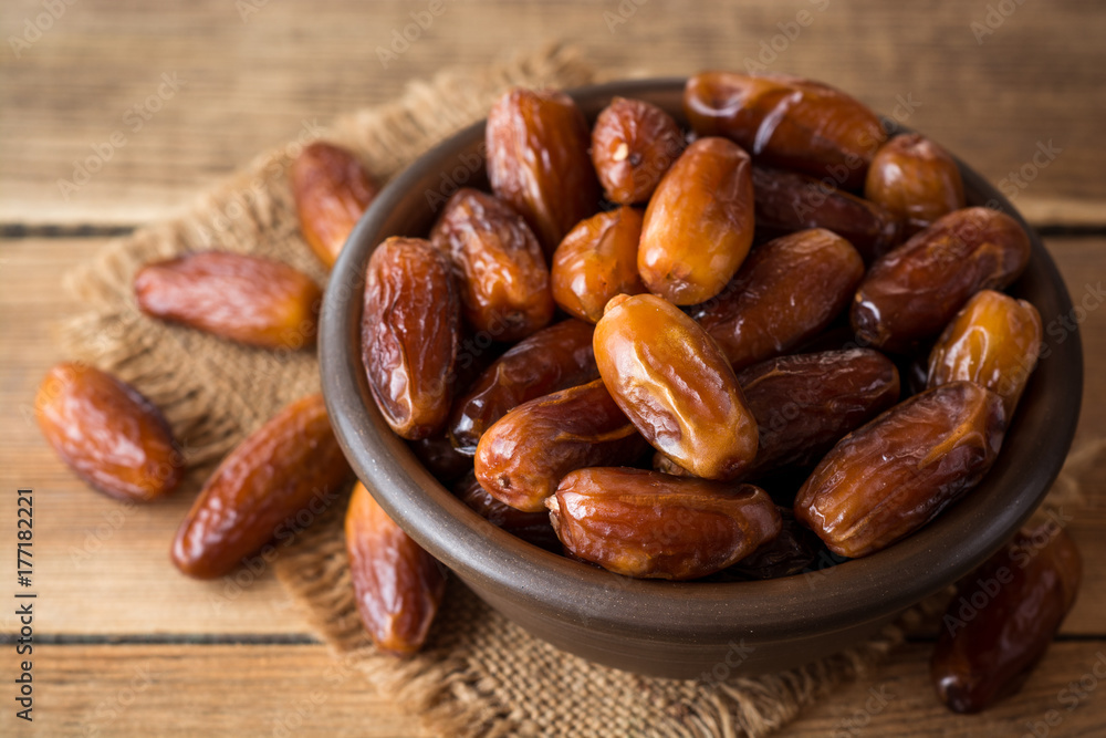 Dried dates fruit in ceramic bowl on wooden table. Dried dates fruit in ceramic bowl on wooden table.
