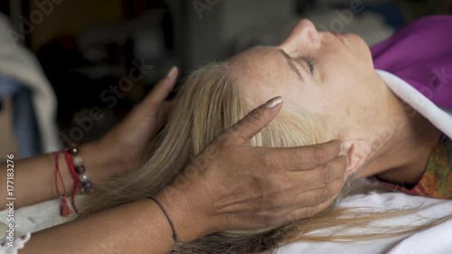 Very tight shot of a polarity therapist with her hands near her patient’s head feeling her energy.