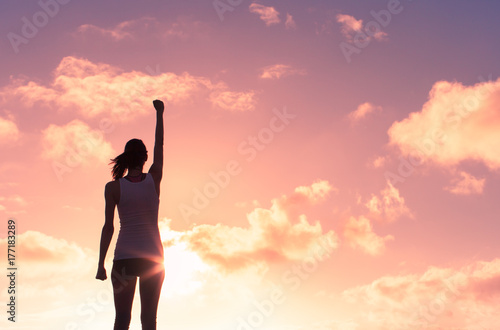 Girl power! Silhouette of strong victorious woman with her fist in the air. 