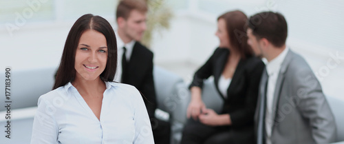 Successful business woman standing with her staff in background 