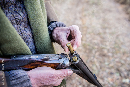 Old man putting ammunition in a hunting rifle-(loading shotgun) photo