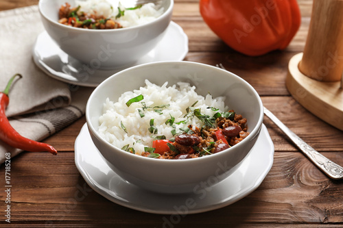 Chili con carne served with rice in bowl on wooden table