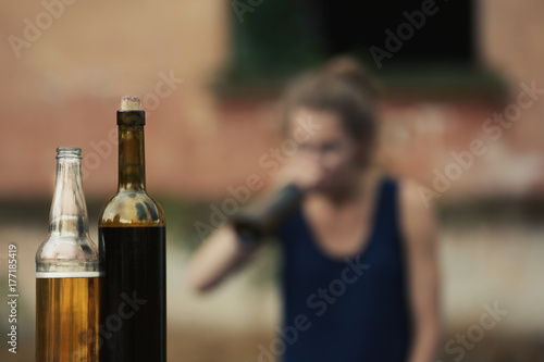 Bottles with alcohol on blurred view of drunk woman