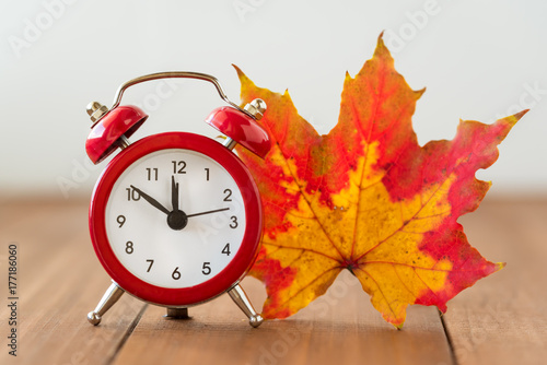 Red vintage clock and mable leaf. Autumn time change