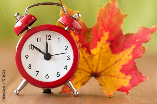 Red vintage clock and mable leaf. Autumn time change