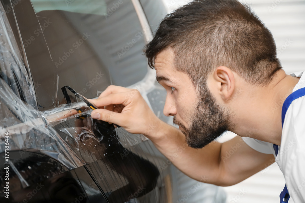 Worker tinting car window in shop Worker tinting car window in shop