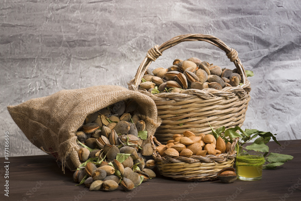 Almonds over rustic wooden board. / Almonds over a rustic wooden board. Rustic sack and basket. Nutcracker and almond oil. Almonds over rustic wooden board. / Almonds over a rustic wooden board. Rustic sack and basket. Nutcracker and almond oil.