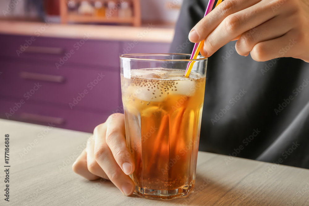 Woman holding glass of tea with chia seeds on table Woman holding glass of tea with chia seeds on table