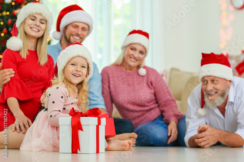 Little girl with Christmas gift and her family at home