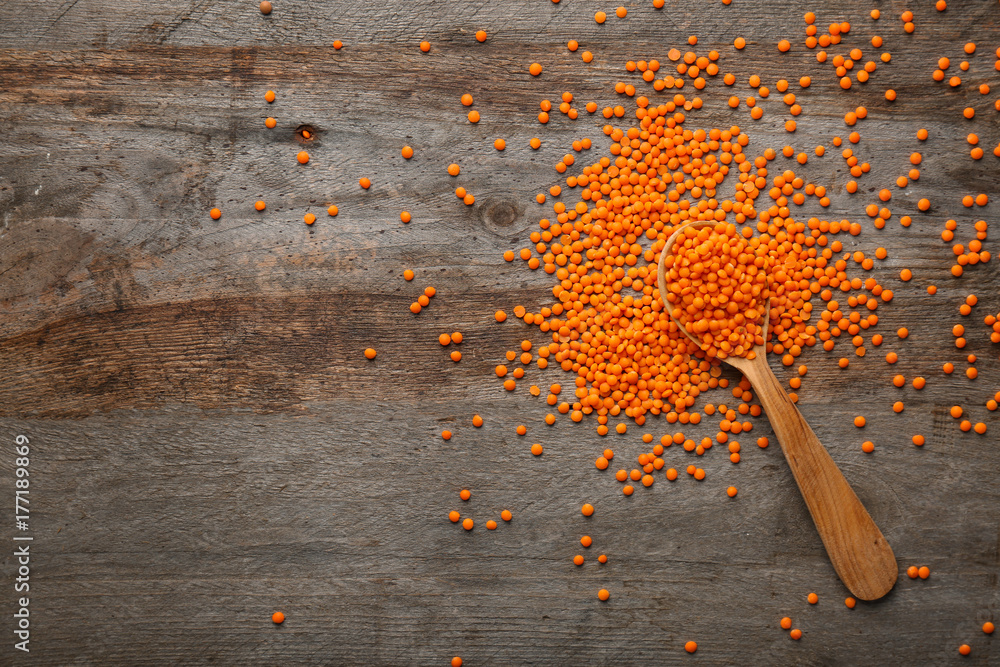 Spoon with red lentils on wooden table Spoon with red lentils on wooden table