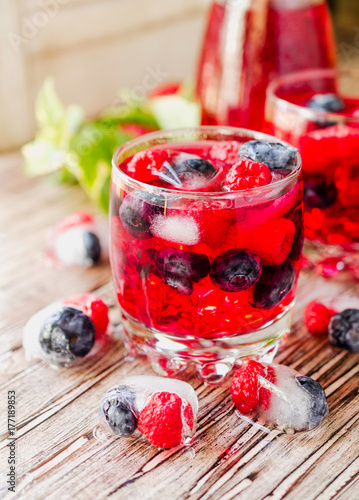 Summer berry lemonade with frozen berries on a wooden rustic table, selective focus