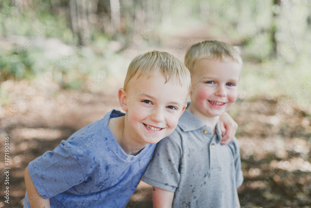 Smiling brothers stop to take a photo during nature walk in woods Smiling brothers stop to take a photo during nature walk in woods
