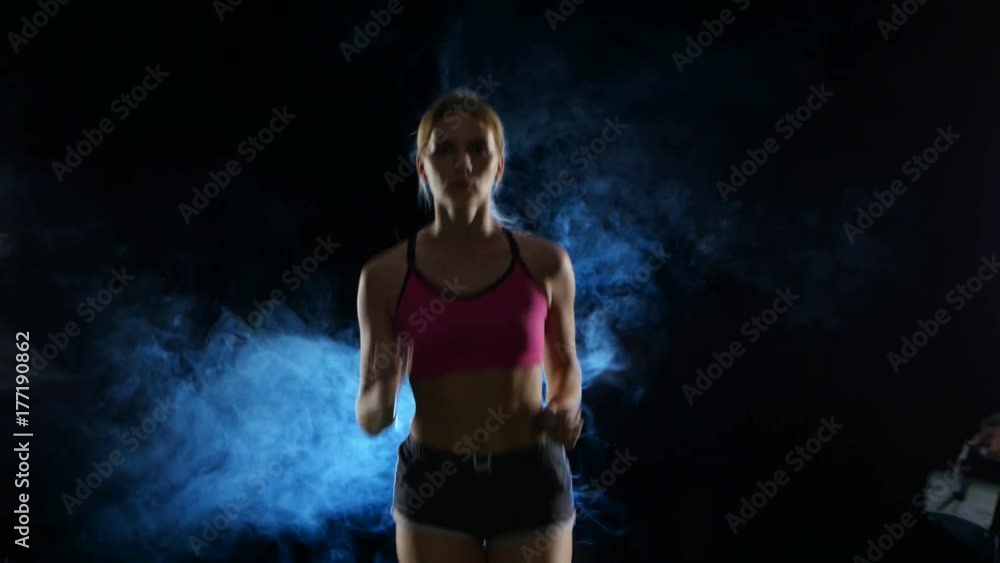 Girl fitness runs steadily. Front view. Black screen in the smoke. Close up Girl fitness runs steadily. Front view. Black screen in the smoke. Close up