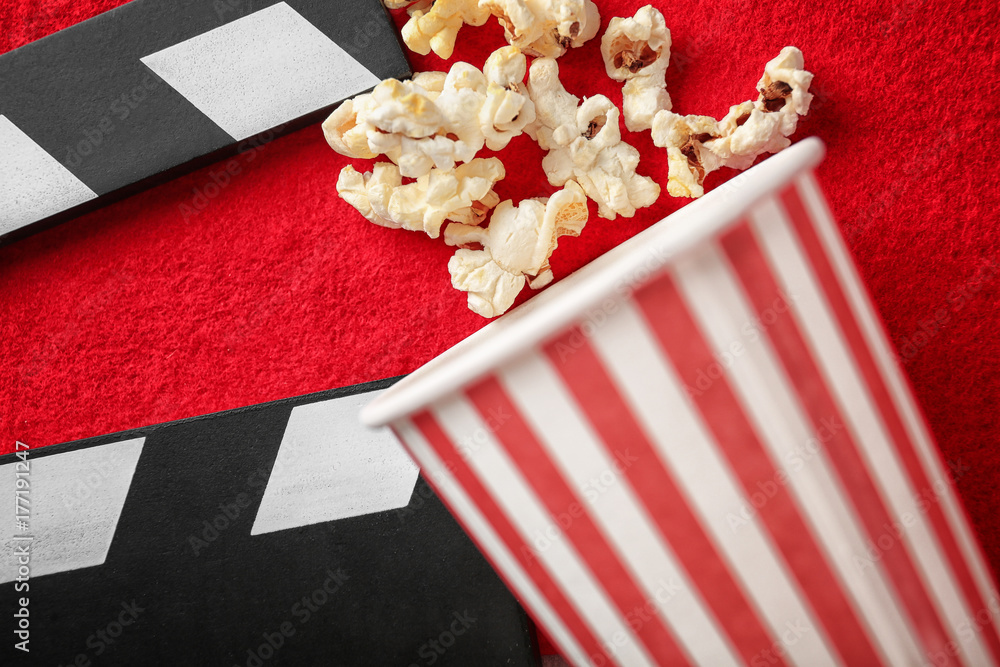 Movie clapper and cup of popcorn on red carpet