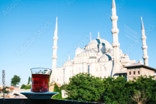 Traditional aromatic Turkish black tea in a tulip-shaped glass. In the background, the Blue Mosque is also called Sultanahmet in Istanbul, Turkey.
