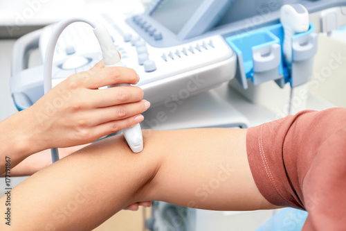 Doctor conducting ultrasound examination of patient's elbow in clinic