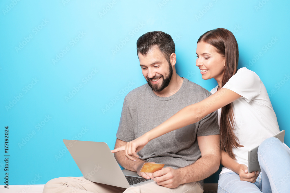 Young couple with laptop and tablet computer near color wall. Internet shopping concept Young couple with laptop and tablet computer near color wall. Internet shopping concept
