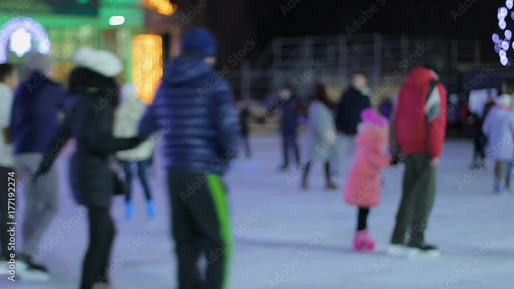 Cheerful young people and families skating on ice rink, active recreation Cheerful young people and families skating on ice rink, active recreation