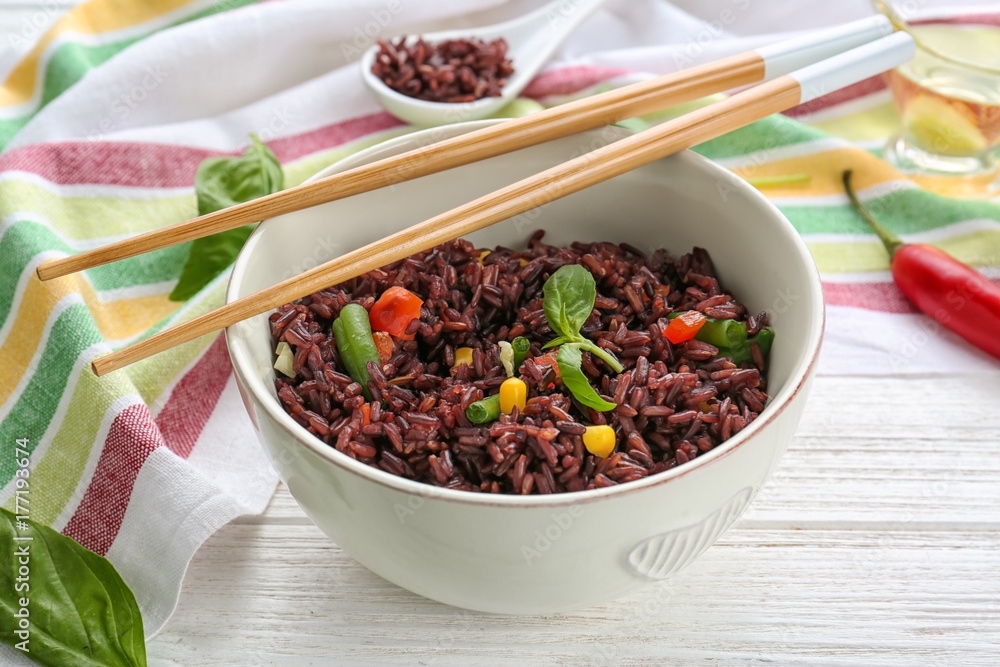 Bowl with red rice and vegetables on wooden table Bowl with red rice and vegetables on wooden table