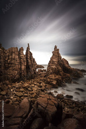 Dramatic long exposure of grey clouds over a rugged coastline