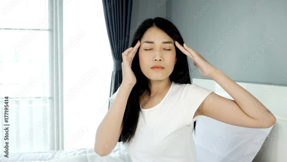 4k of Depressed Beautiful Asian woman sitting on her bed at home. woman massaging her temples 4k of Depressed Beautiful Asian woman sitting on her bed at home. woman massaging her temples