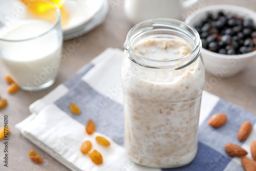 Jar with tasty oatmeal and milk on table