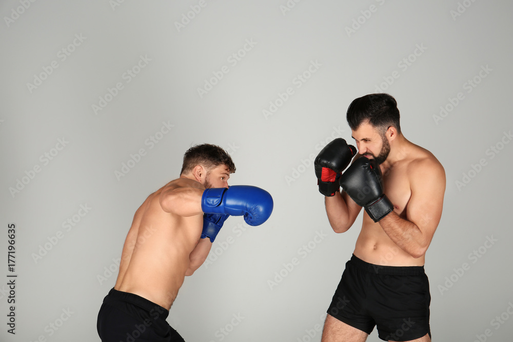 Male boxers fighting on light background
