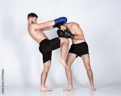 Male kickboxers fighting on white background