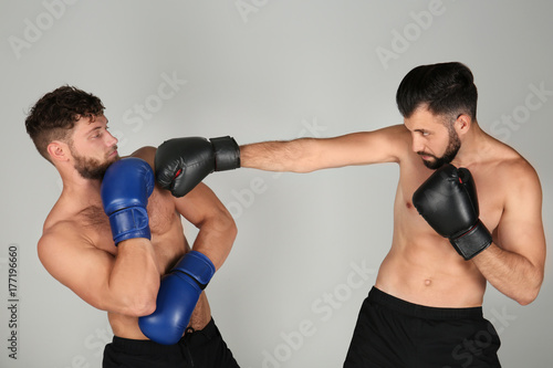 Male boxers fighting on light background © Africa Studio