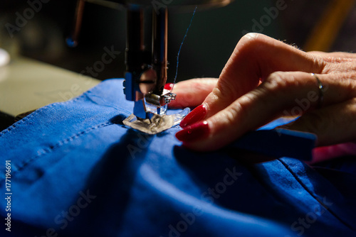 Fototapeta Naklejka Na Ścianę i Meble -  Close up on sewing machine and seamstress' hand while she is working