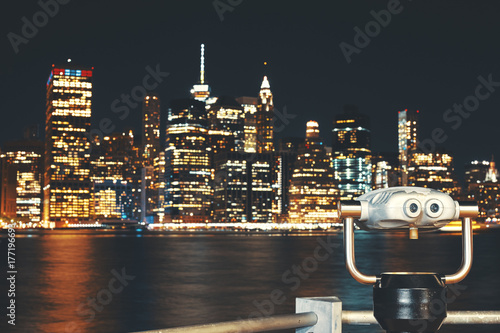 New York City skyline with binoculars at night, color toning applied, focus on foreground, USA. 