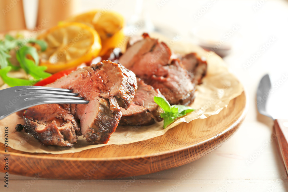 Fork and sliced tasty steak on wooden plate Fork and sliced tasty steak on wooden plate